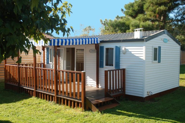 Mobil-home blanc avec terrasse en bois.
