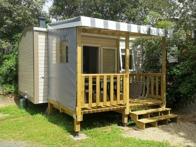 Mobil-home avec terrasse en bois ensoleillée.