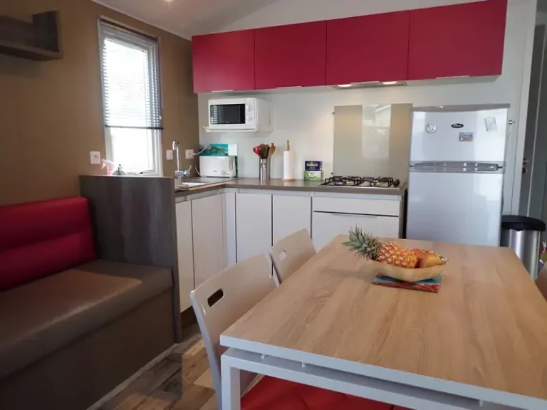 Cuisine équipée d'un mobil-home avec plaques 4 feux, micro-ondes, réfrigérateur-congélateur et coin repas